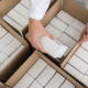 Close-up view of the hands of a manufacturing worker putting packed products in cardboard boxes