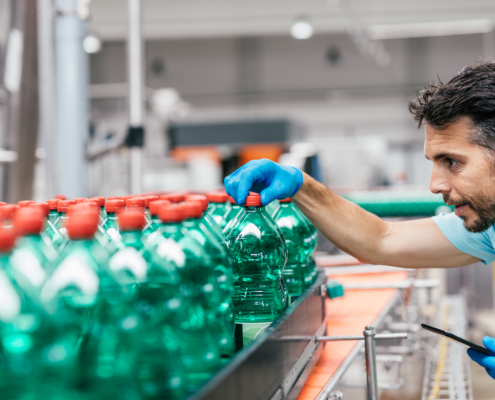 Male worker in bottling factory checking water bottles before shipment